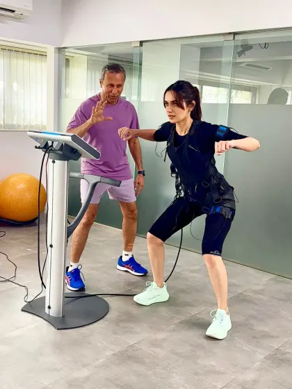 Here, I'm adjusting Manushi's stance to ensure perfect alignment during her EMS workout. Precision is key to smart training.