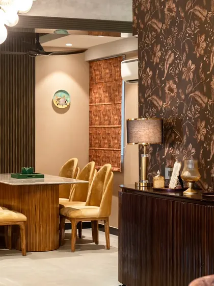 A wider view of the dining room entrance, showing the interplay of different textures, from the wallpaper and fluted console to the smooth marble tabletop and velvet chairs.