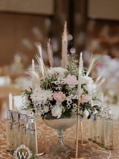 A classic and elegant reception setup symbolizing everlasting love. The stage features a modern, minimalist backdrop with custom monograms, floral arrangements, and soft lighting.