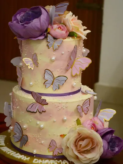 A two-tier cake with a butterfly theme, perfect for a birthday or anniversary. The soft watercolor buttercream and delicate wafer paper butterflies create a dreamy, ethereal look.