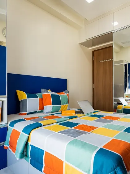 A vibrant kids' bedroom with a bold blue wardrobe and colorful checkered bedding. The mirrored wardrobe doors make the room feel larger and brighter.