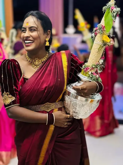 A client celebrating a Thiruvizha (temple festival) in our custom maroon velvet blouse and matching saree. We love creating outfits for such auspicious family occasions.