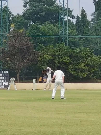 An action shot from the KSCA Under-12 League match between Lions Cricket Club and Eleven Brothers CC, with the official KSCA scoreboard in the background.
