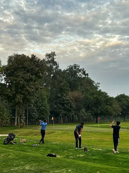 A group of golfers practices under a dramatic, cloudy sky.