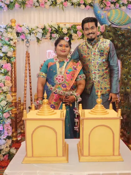 A happy portrait of the couple during their baby shower, standing by the table with the gender reveal temple boxes.