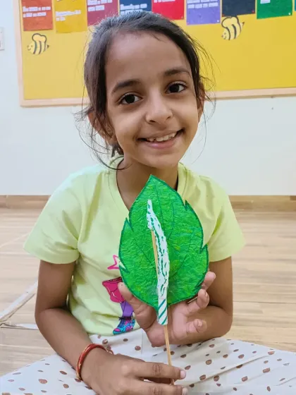 A smiling girl shows off the caterpillar on a leaf she crafted. We love seeing the joy on their faces when they complete a project.