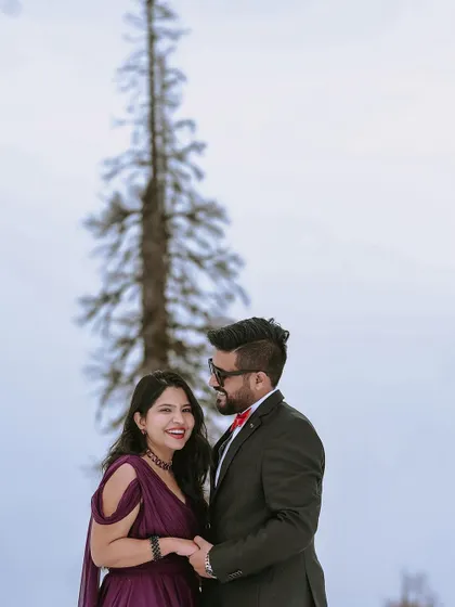A joyful and candid portrait of the couple enjoying the snowfall during their pre-wedding shoot in Kashmir, capturing a moment of pure happiness.