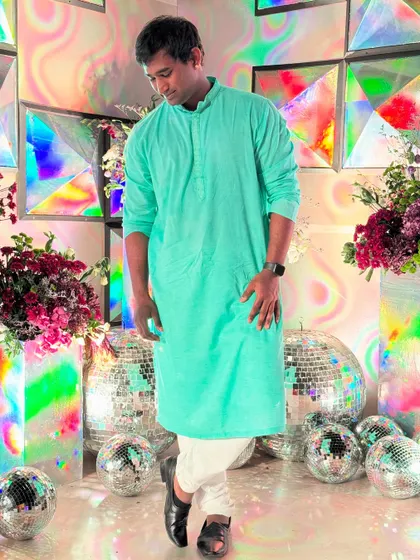 Posing against a vibrant, colorful backdrop at a sangeet. The decor and lighting play a huge role in the final performance.