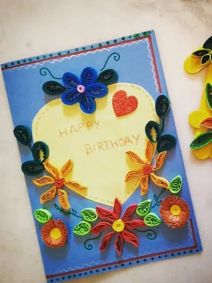 A student's finished paper quilling birthday card. This craft project teaches children patience and precision as they roll and shape paper strips into beautiful floral designs.