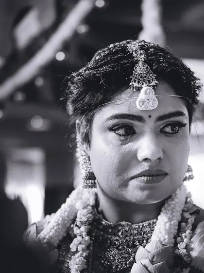 A close-up black and white portrait of the bride, capturing her intense and emotional expression during a key ritual.