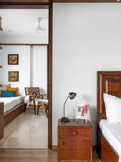 The 'Gulmohar' primary room features a classic wooden bed and a full-height sliding wardrobe in a neutral palette to create a serene and timeless feel.