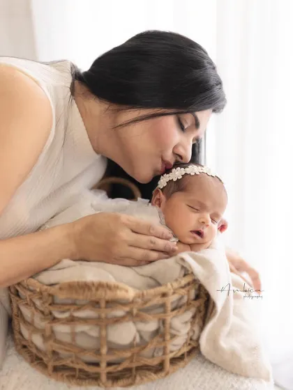 A mother's gentle kiss for her sleeping newborn, nestled in a rustic basket. This tender moment is a perfect example of the love and softness I capture in my parent and child sessions.
