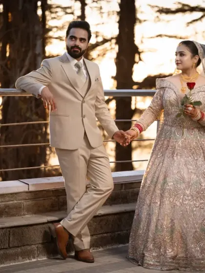The couple holds hands, standing on a balcony as the sun sets behind the pine trees. A perfect end to a perfect day of shooting.