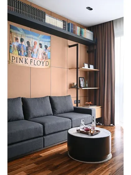 Another angle of the lounge room, highlighting the cork sheet paneling and custom shelving. The design incorporates personal touches like a Pink Floyd poster, creating a space that is both stylish and deeply personal for the client.