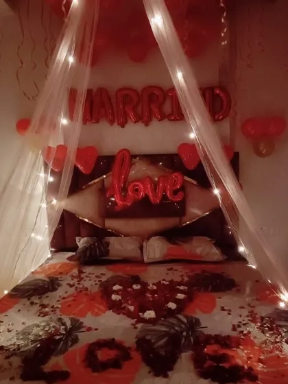 A classic romantic room decoration for a wedding night or anniversary. I used "MARRIED" and "love" foil balloons, a canopy over the bed with fairy lights, and scattered rose petals to create a sweet and intimate surprise.