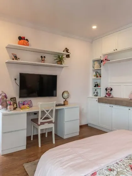 The study area in the girl's bedroom is designed with plenty of shelving and a spacious desk, creating a perfect spot for homework and creative projects.