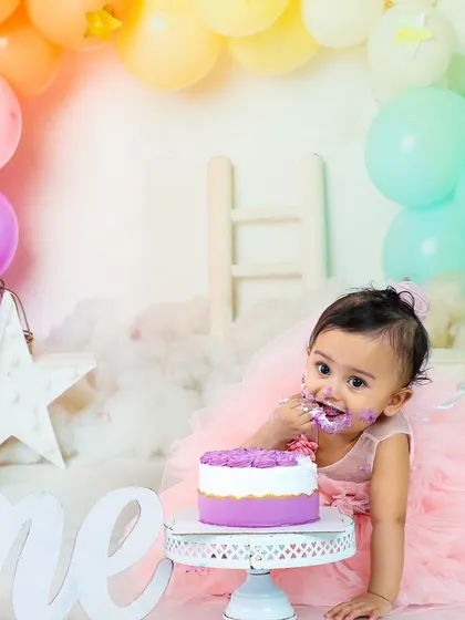 A sweet and slightly messy moment. This little girl in her pink tulle dress is delicately tasting the frosting from her first birthday cake.