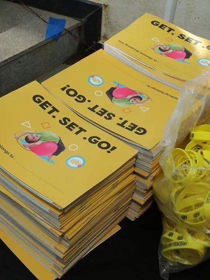 A duplicate shot of the stacked brochures and wristbands for the event.