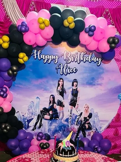 A K-Pop Blackpink themed birthday party. The setup includes a custom backdrop with the band's photo, framed by a black, pink, and purple balloon arch.