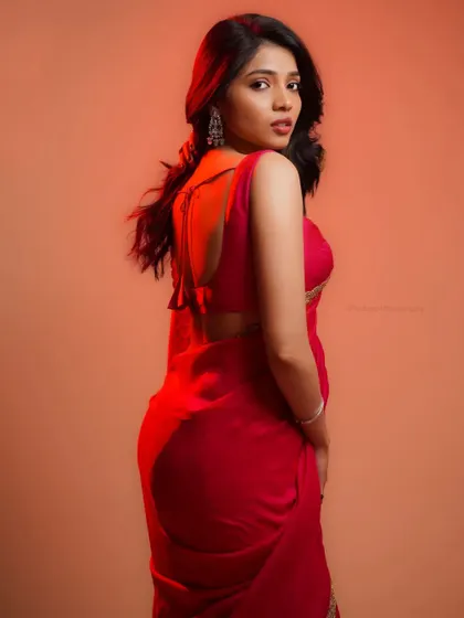 A dramatic portrait using colored lighting. The red light adds intensity and a modern edge to this traditional saree look.