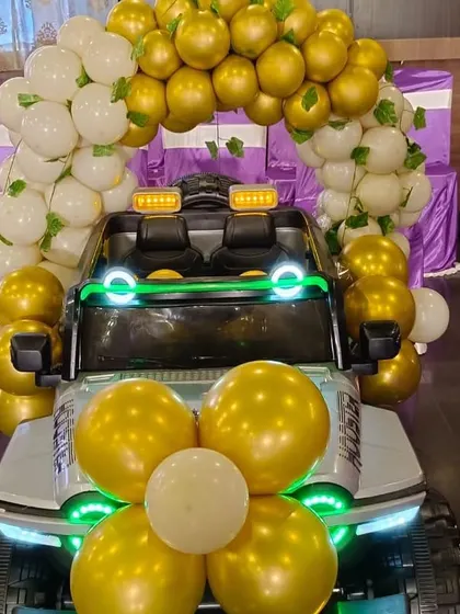 A fun detail from an animal-themed party: a toy jeep decorated with a gold and white balloon garland.