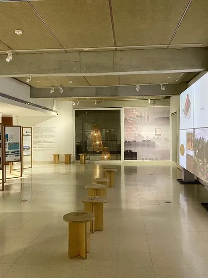 An overview of the "Small is beautiful" exhibition layout. The open plan, punctuated by custom stools and large-format digital screens, creates a flexible environment for learning and interaction, reflecting the exhibition's theme of sustainable innovation.