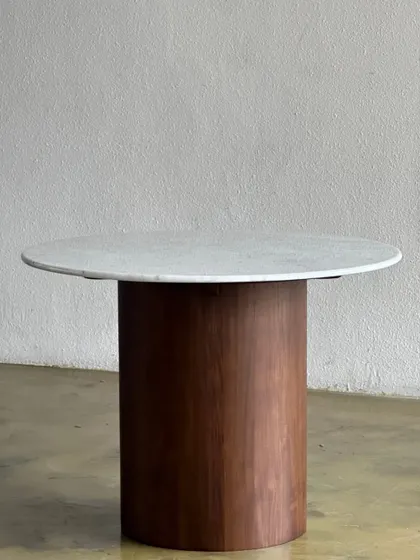 A minimalist round cafe table with a white marble top and a solid cylindrical wooden base. This design is sturdy and easy to clean, ideal for busy cafes.
