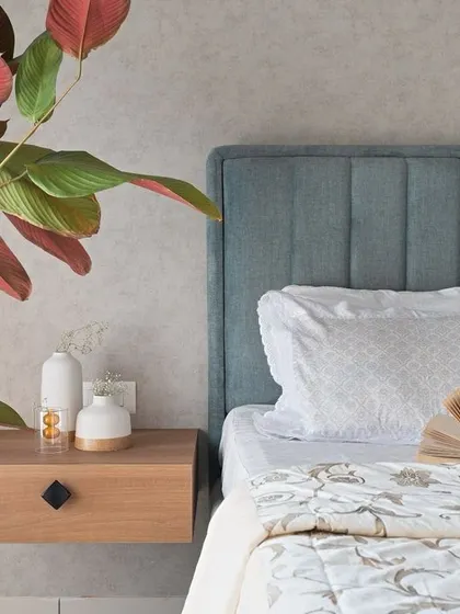 A close-up in the pastel bedroom, showing the floating nightstand and the beautiful texture of the upholstered headboard.