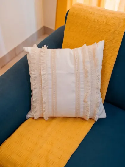 This textured white cushion with delicate ruffled details adds a touch of boho charm to the teal sofa. It's a great way to add texture and soften the look of a bold piece of furniture.