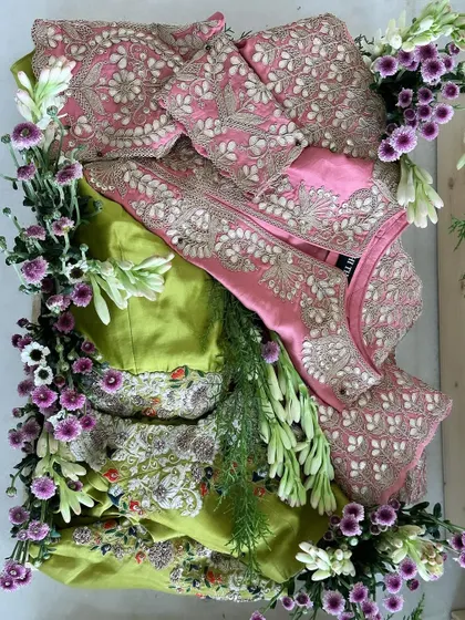 A stunning combination of a pink embroidered outfit and a green one, both decorated with fresh, fragrant tuberoses and other delicate flowers.