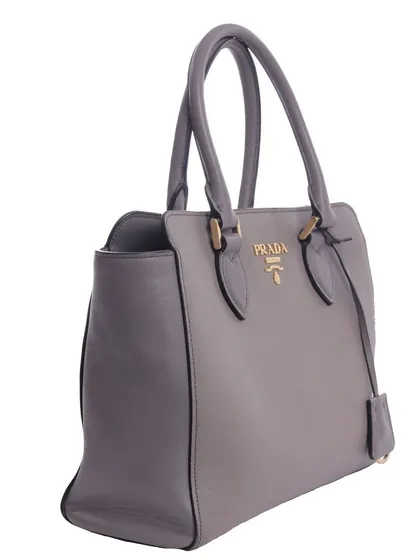 A side-angle shot of a grey Prada handbag, highlighting its shape, structure, and leather texture for a luxury resale or e-commerce site.