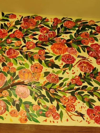 A full view of the floral tree mural inside the boutique. The branches are filled with vibrant orange and pink flowers, creating a beautiful and eye-catching feature wall.