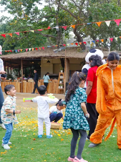 Kids and costumed characters dancing and playing together at the Holi carnival.