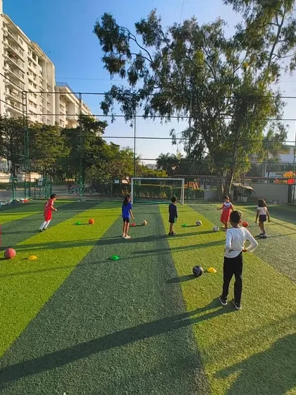 A wide view of our football class on a sunny day, with kids spread out across the turf, engaged in various drills.