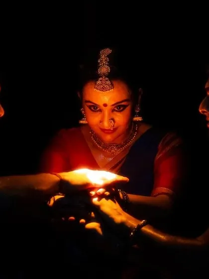 A scene from 'Naga Mandala' where the dancers' hands are illuminated by a single flame. This symbolizes the central themes of the story.