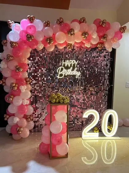 For a 20th birthday, this pink sequin wall is paired with a pink and white balloon arch and illuminated numbers.