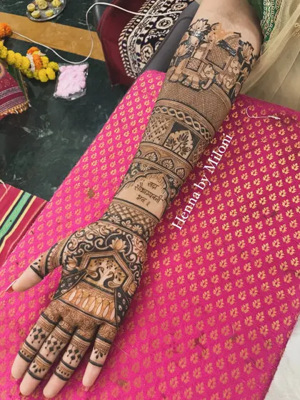 A full-arm bridal mehendi with personalized text and traditional motifs. The design includes elephants, lotuses, and a swan, creating a rich and meaningful pattern.
