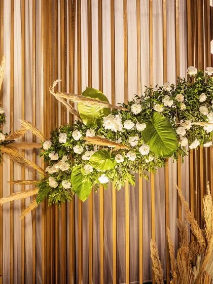 A detailed shot of the floral arrangement on the modern mandap, highlighting the use of fresh white flowers and lush greenery.