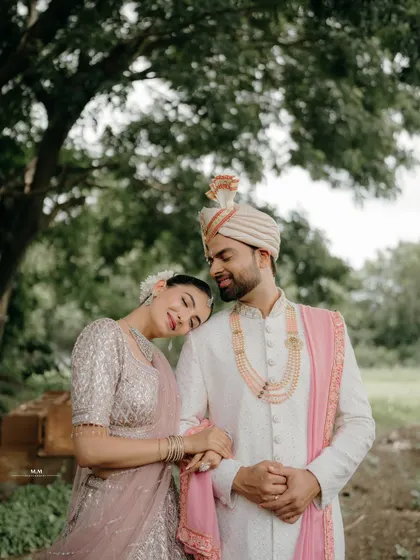 She rests her head on his shoulder, a picture of contentment and love. Their coordinated outfits and the natural setting create a beautiful and serene portrait.