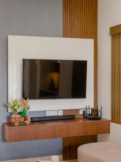 This Chennai home proves beauty lies in simplicity. The TV unit features a clean, minimalist design with a floating white console and a wood-paneled accent.