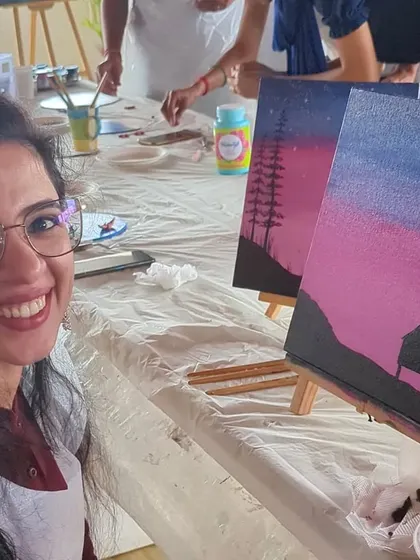A participant smiling proudly with her finished nightscape canvas painting.