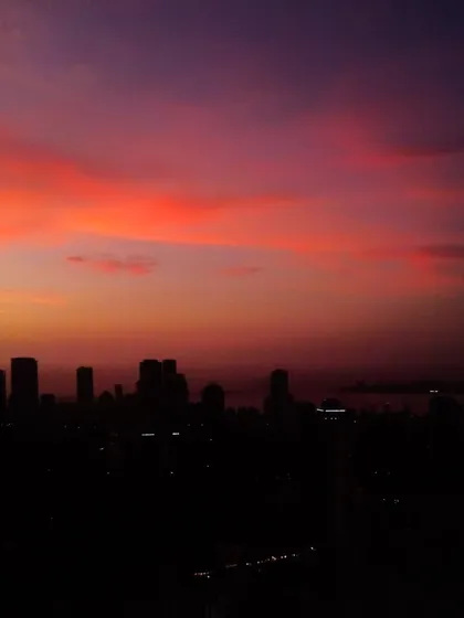 A view of the Mumbai skyline at dusk, with the sky painted in deep shades of purple and red.