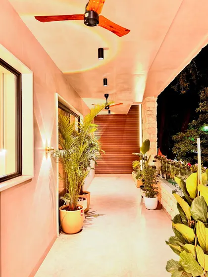 A view of a residential balcony at night. I used a combination of wall sconces and spotlights to create a warm and inviting outdoor space. The abundance of potted plants makes this long balcony feel like a private garden, perfect for relaxing in the evening.