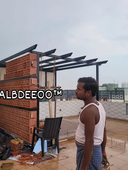 A wider view of the pergola structure during construction. The combination of the modern black MS frame and the earthy, patterned terracotta wall creates a unique and stylish aesthetic right from the build stage.