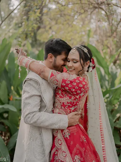 A sweet, candid embrace surrounded by lush greenery, capturing a natural moment of affection on their wedding day.