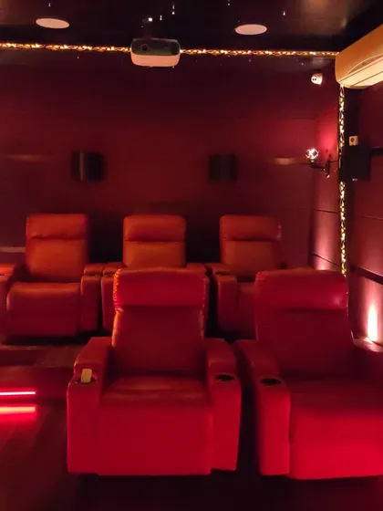 A compact yet powerful home theater with bold red recliners and matching red floor lighting. We can transform rooms of any size into a dedicated cinema space with professional acoustic treatment and equipment.