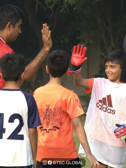 A young goalkeeper high-fives his coach, a moment of connection and encouragement. Our coaches are mentors who build confidence and celebrate every player's contribution.