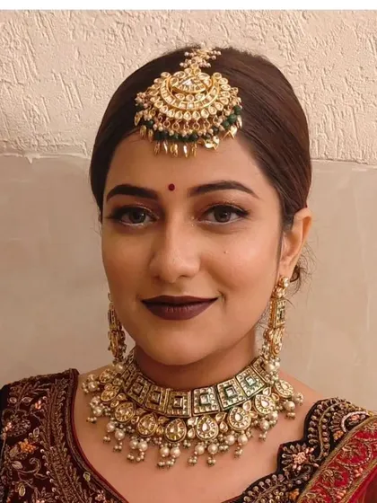 A simple and elegant look featuring a Pachi Kundan choker with green stones and a matching maang tikka.