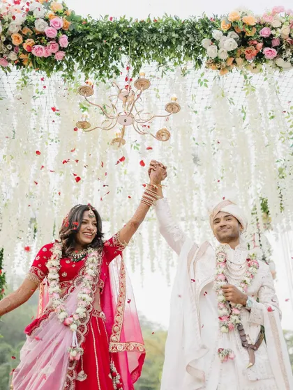 A moment of pure triumph and joy. Sanket and Sakshi celebrate their union under a shower of petals, their hands raised in a beautiful, celebratory pose.