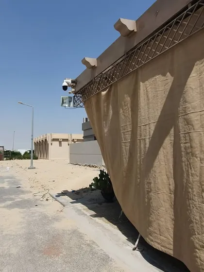 A wide shot of an outdoor installation in a desert environment. The cameras are positioned to monitor the perimeter of the property.